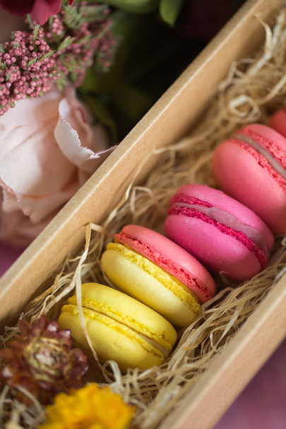 Row of cake macaroons in gift box on bright background. Close up macaron dessert on top view. Colorful almond cookies in pastel pink, yellow colors. Vintage style. - Fotó, kép