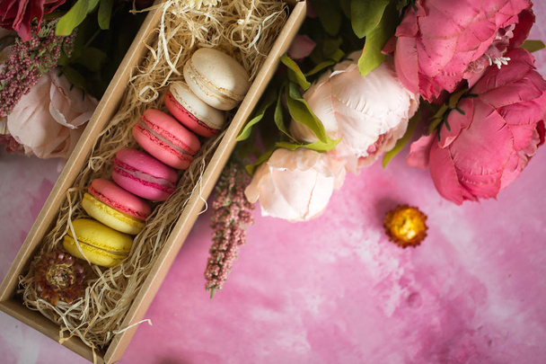Row of cake macaroons in gift box on bright background. Close up macaron dessert on top view. Colorful almond cookies in pastel pink, yellow colors. Vintage style. - Φωτογραφία, εικόνα