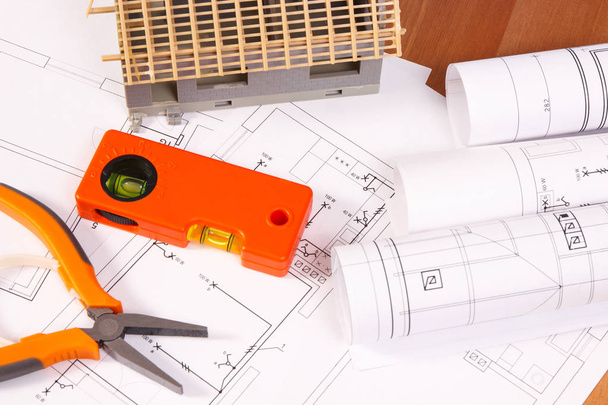 Dibujos o diagramas eléctricos, herramientas de trabajo naranjas para trabajos de ingeniería y casas en construcción, concepto de casa de construcción
 - Foto, Imagen