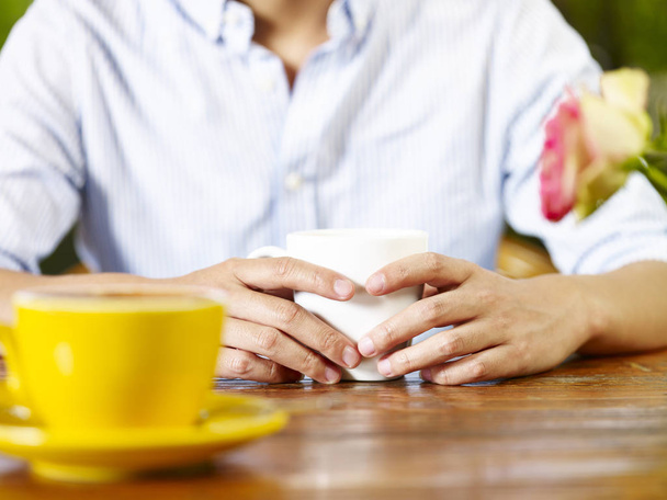 mladý muž v konverzaci při pití kávy nebo čaje, se zaměřují na rukou. - Fotografie, Obrázek