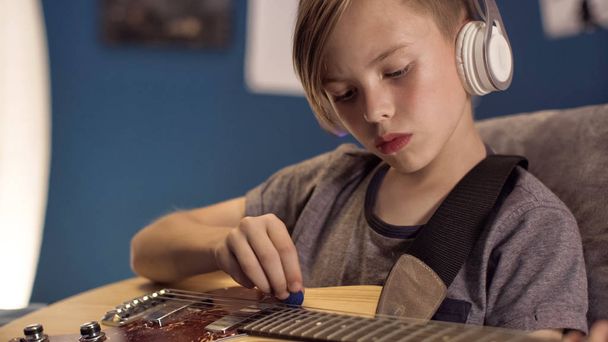 Jongen in hoofdtelefoons lied met gitaar leren - Foto, afbeelding
