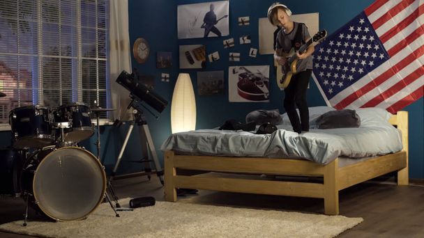 Expressive youngster playing guitar in bedroom - Photo, Image