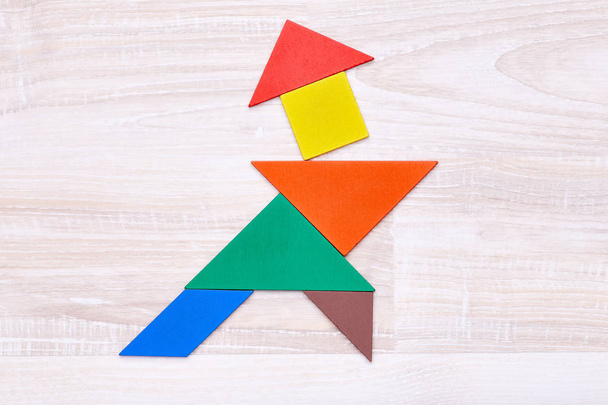 Flay leggen van kleurrijke tangram cijfers gerangschikt in de vorm van samoerai op houten tafel - Foto, afbeelding