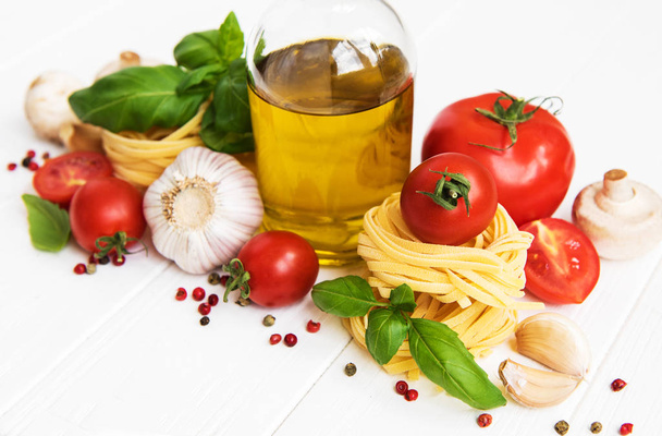 Інгредієнти італійської кухні, оливкова олія, спеції, макарони і помідори на білий дерев'яний стіл - Фото, зображення