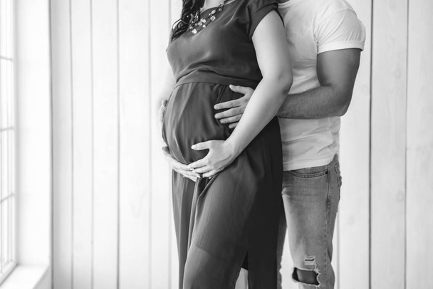 Pretty pregnant woman hugging with husband indoors - Valokuva, kuva