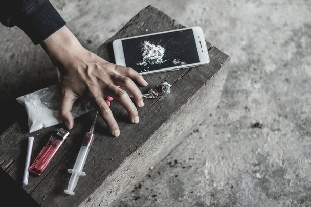 Молодая человеческая рука пытается достать наркотики, понятие преступности и наркомании. 26 июня, Международный день борьбы с наркоманией и незаконным оборотом наркотиков
 - Фото, изображение