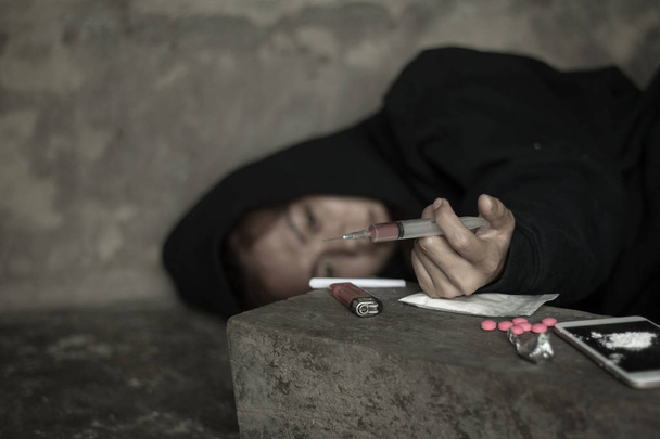 La mujer que sostiene la jeringa y la sobredosis, el concepto de crimen y adicción a las drogas. 26 de junio, Día Internacional contra el Abuso de Drogas y el Tráfico Ilícito
 - Foto, Imagen