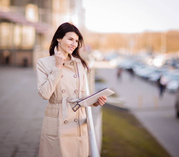 Modern business woman working on a digital tablet, standing next to an office building - Foto, Bild