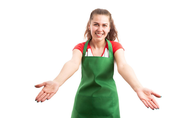 junge Einzelhandelskauffrau oder Supermarkt-Mitarbeiterin macht Willkommensgeste mit den Händen als Gastfreundschaftskonzept für Mitarbeiter isoliert auf weißem Hintergrund - Foto, Bild