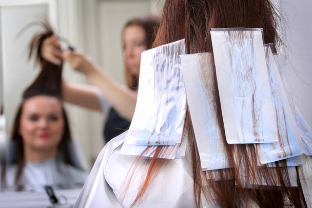 Κορίτσι στο σαλόνι ομορφιάς ενώ ένα στιλίστα τρίχας βαφή μαλλιά - Φωτογραφία, εικόνα