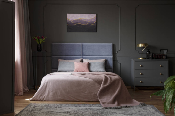 Pastel blanket on bed in pink and blue bedroom interior with gold lamp on grey cabinet - Foto, Imagem
