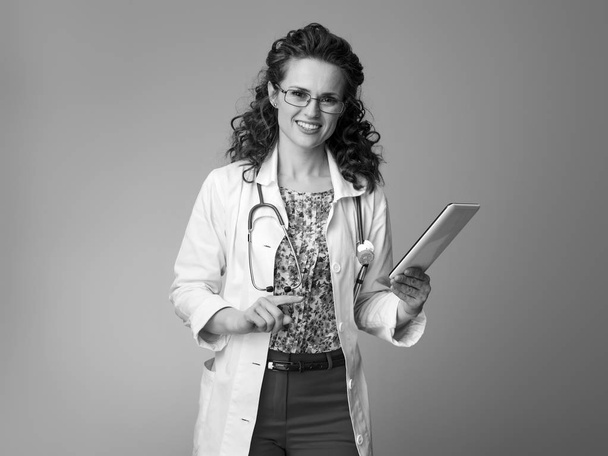 smiling pediatrician woman in white medical robe using tablet PC  - Fotó, kép