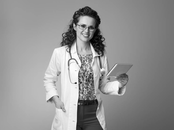 smiling pediatrician woman in white medical robe using tablet PC - Fotó, kép