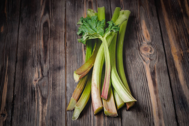 Stems of fresh young rhubarb Ingredients for food recipes healthy diet detox organic food vegetables on wooden background, low key copy space place for text top view soft selective focus - Fotoğraf, Görsel