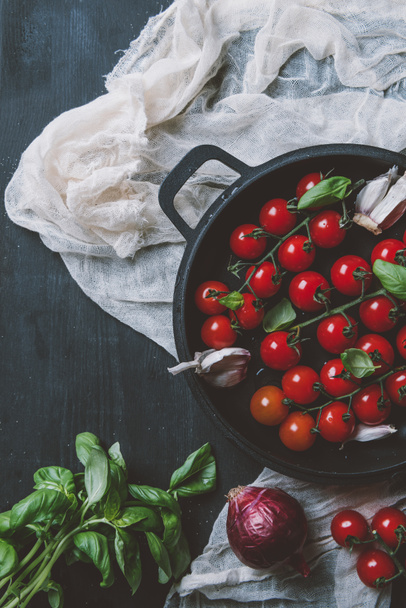 top view of cherry tomatoes, garlic and basil leaves in frying pan on gauze on wooden background - Φωτογραφία, εικόνα