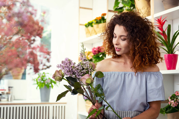 Pleasant creative woman looking at the flowers - Фото, зображення