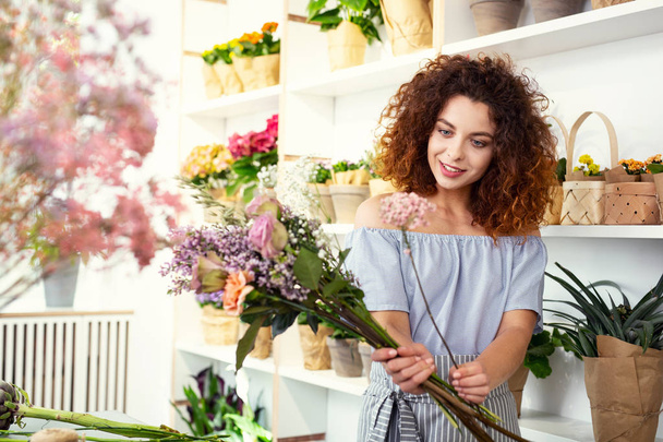 Pleasurable mood. Delighted nice woman smiling while choosing a bouquet - Photo, Image