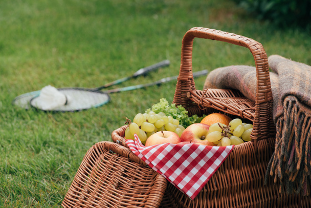 delicious fruits in basket on green grass in park - Foto, afbeelding