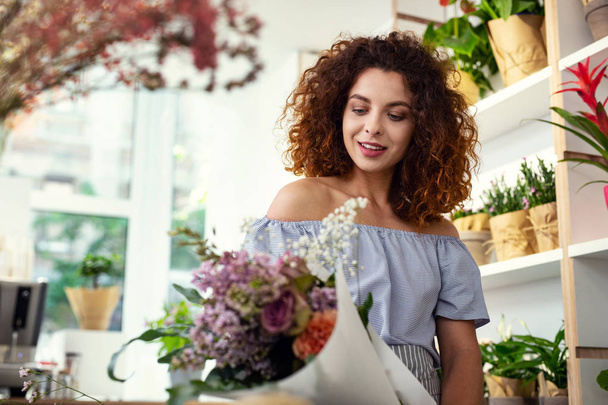 Pleasant attractive woman looking at the flower bouquet - Photo, Image