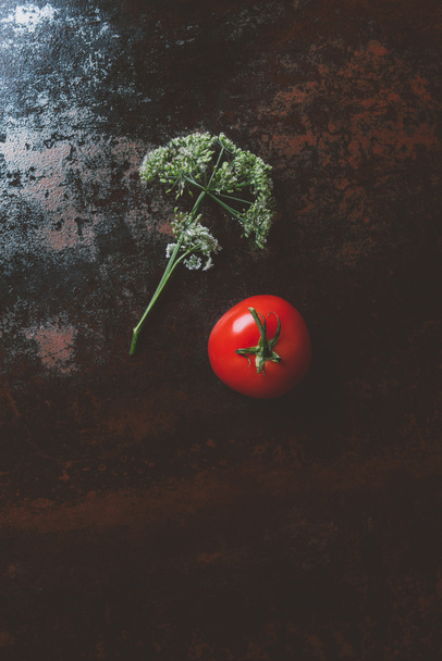 top view of red tomato and parsley flower on rusty background - Fotó, kép