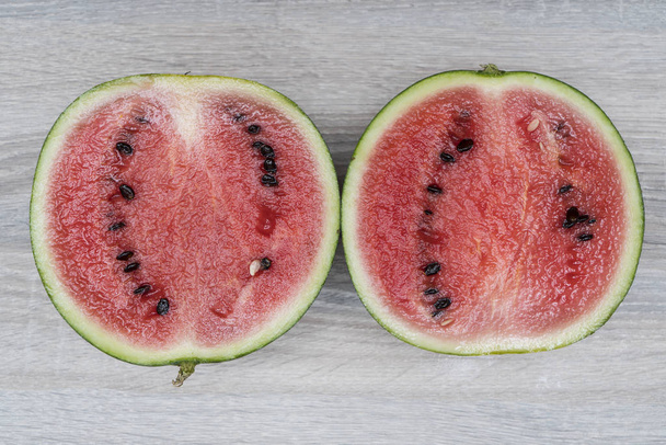 a watermelon cut on a wooden table - Zdjęcie, obraz