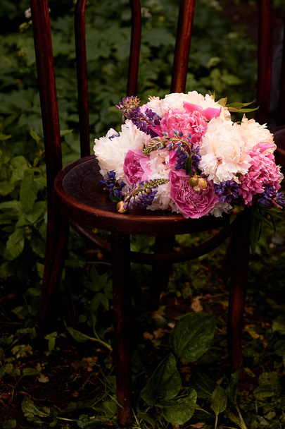 The brides bouquet of peonies is on an old wooden chair.Wedding floristry - Photo, image