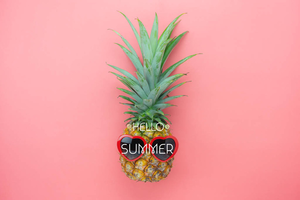 Table top view aerial image of summer & travel beach holiday in the season background concept.Flat lay sign objects on season.Pineapple wear red sunglasses on pink paper with word hello seasonal. - Photo, image