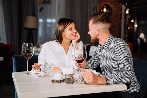 Flirting in a cafe. Beautiful loving couple sitting in a cafe enjoying in wine and conversation - Foto, imagen