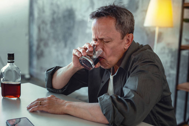 Concerned man feeling stressed drinking alcohol - 写真・画像