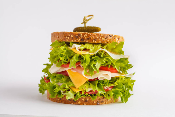Nagy szendvics, saláta, sajt, hús (sonka), paradicsom, elszigetelt fehér. - Fotó, kép
