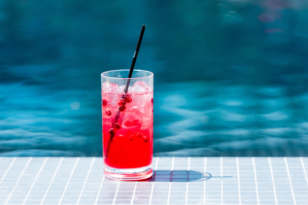 close-up shot of glass of red berry cocktail on poolside - Photo, Image
