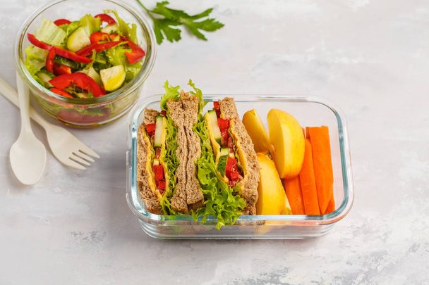 Healthy meal prep glass containers with cheese vegetables sandwiches and vegetable salad overhead shot with copy space - Fotó, kép