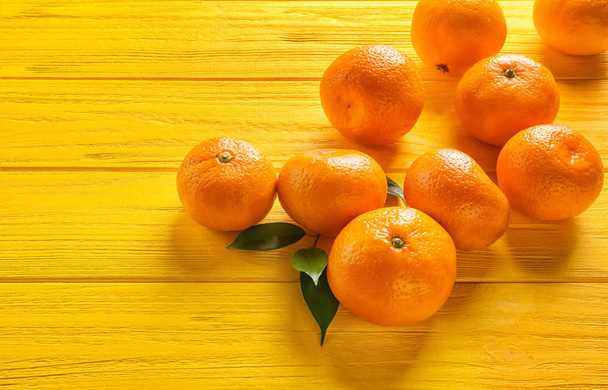 Juicy tangerines on color wooden table - 写真・画像