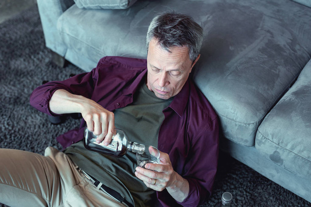 Wrinkled mature man pouring whisky in his glass - Valokuva, kuva