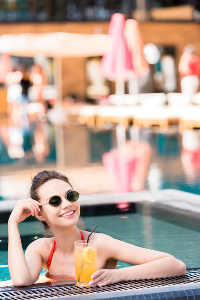 krásná mladá žena s vynikající oranžový koktejl relaxaci v bazénu - Fotografie, Obrázek