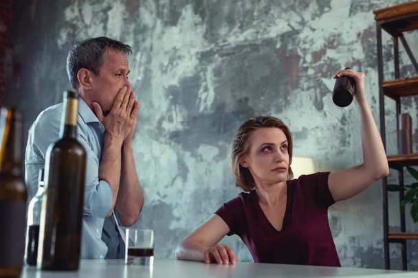 Drunk wife with blue eye sitting near sober disturbed man - Foto, Bild
