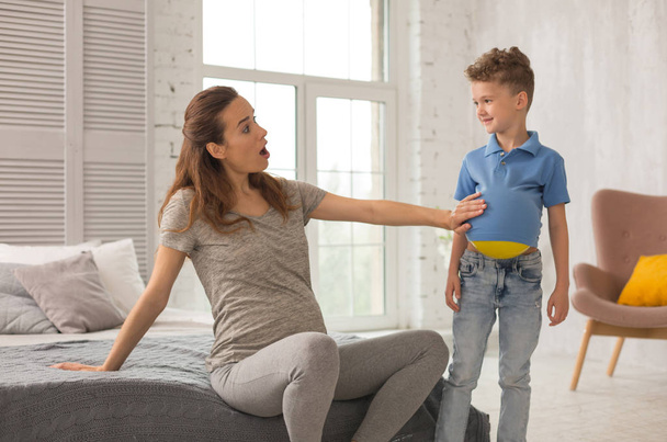 Pregnant mother wearing grey shirt and leggings cheering up her son - Photo, image