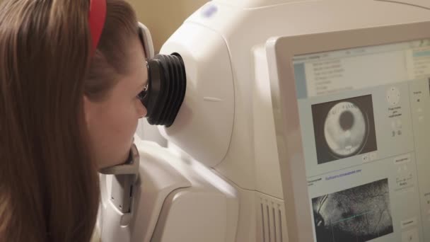 Woman is sitting in front of tomography apparatus in ophthalmological clinic - Footage, Video