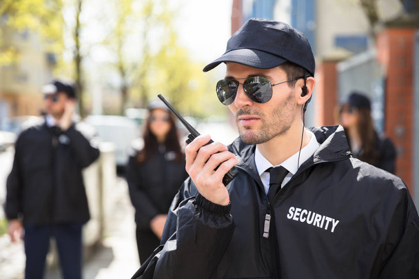 Portrait Of A Male Security Guard Talking On Walkie Talkie - Foto, afbeelding