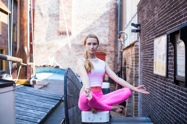 Portrait blonde yoga girl in morning city Groningen, woman with long blond hair meditating and  doing yoga exercisers in city street, healthy lifestyle concept - Photo, Image