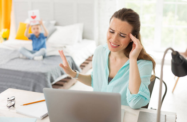 Remote worker feeling disturbed by her little son - Photo, image