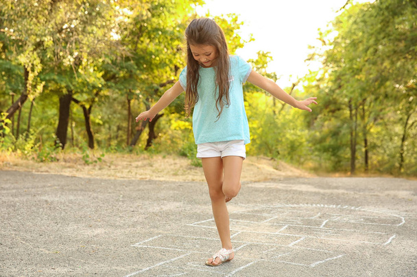 Cute little girl playing hopscotch, outdoors - 写真・画像
