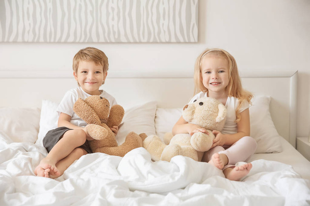 Милі діти з іграшками на ліжку вдома
 - Фото, зображення