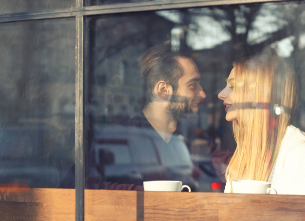 Jeune couple romantique dans un café, vue de l'extérieur par la fenêtre
 - Photo, image