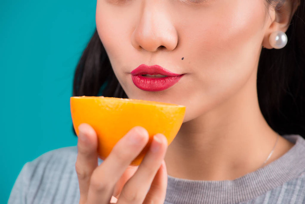 Egészséges étel. Közeli kép a dmiling szép luxus ázsiai lány holding narancs fölött kék háttér. - Fotó, kép