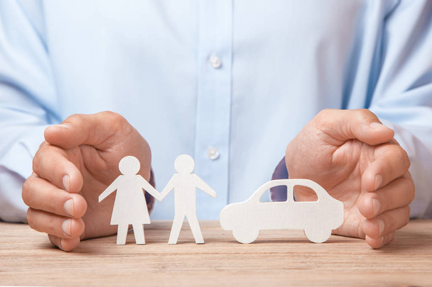 Pojištění, mladé rodiny a auto. Muž v košili pokrývá ruce s rodinou muže a ženy a auto - Fotografie, Obrázek