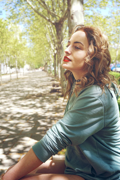 photo of young curly woman in green sweater outdoor on park in summer - Photo, Image