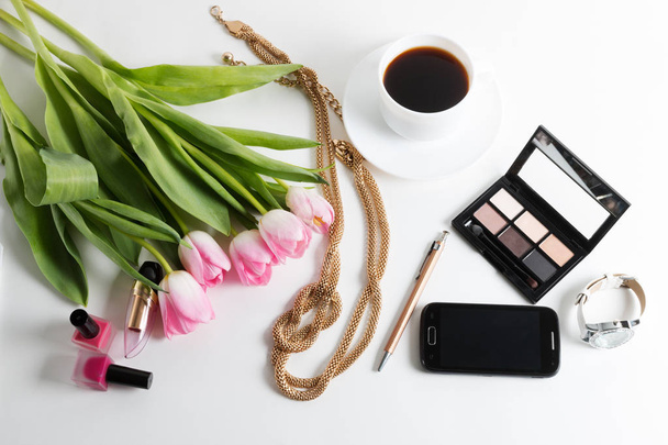 Pink tulips, bijouterie, cosmetics, pen, wristwatch, coffee on white - spring female things - 写真・画像