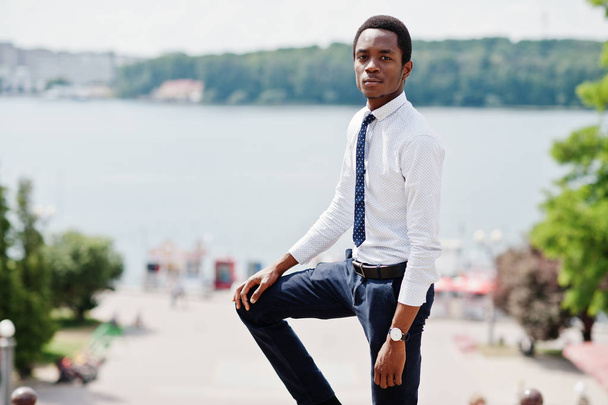 Stylish african american business man at pants and shirt posed outdoor against lake. - Фото, изображение