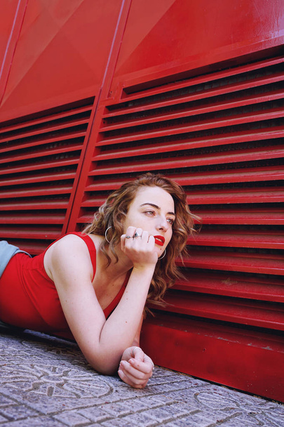 photo of young beautiful curly woman in red shirt outdoor in summer time  - 写真・画像